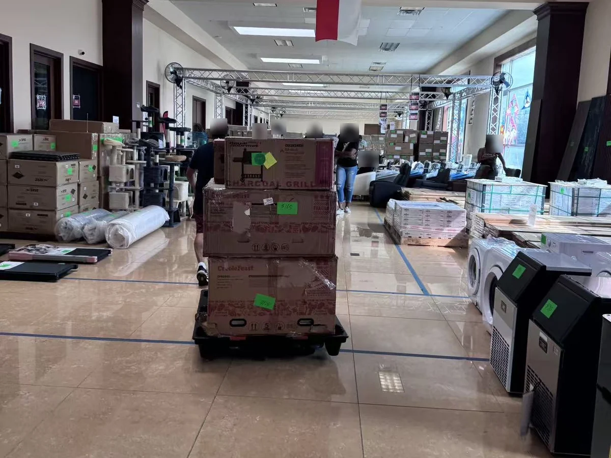 A charcoal grill and a crawfish boiler boxed on a pallet trolley in the aisle of the Cube-Age Houston sale