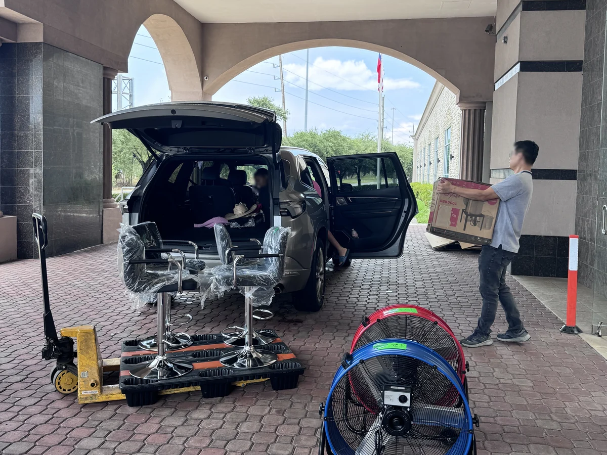 Bar stools, floor fans and a boxed grill kit being loaded into one vehicle at the Cube-Age Houston sale