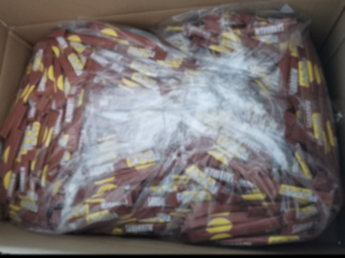 A carton of individually wrapped brown cane sugar sticks as it arrives