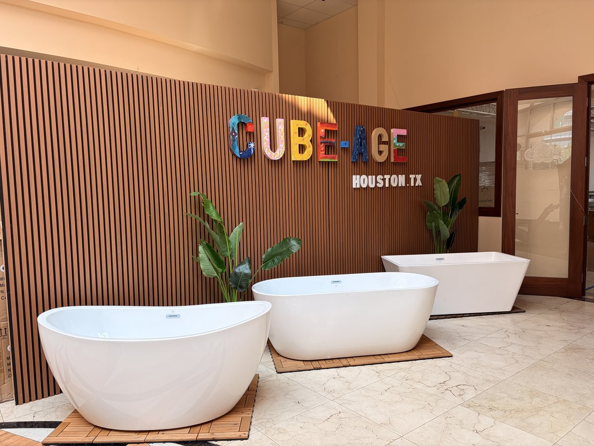 The CUBE-AGE brand wall inside the entrance, with three freestanding bathtubs displayed in front of it