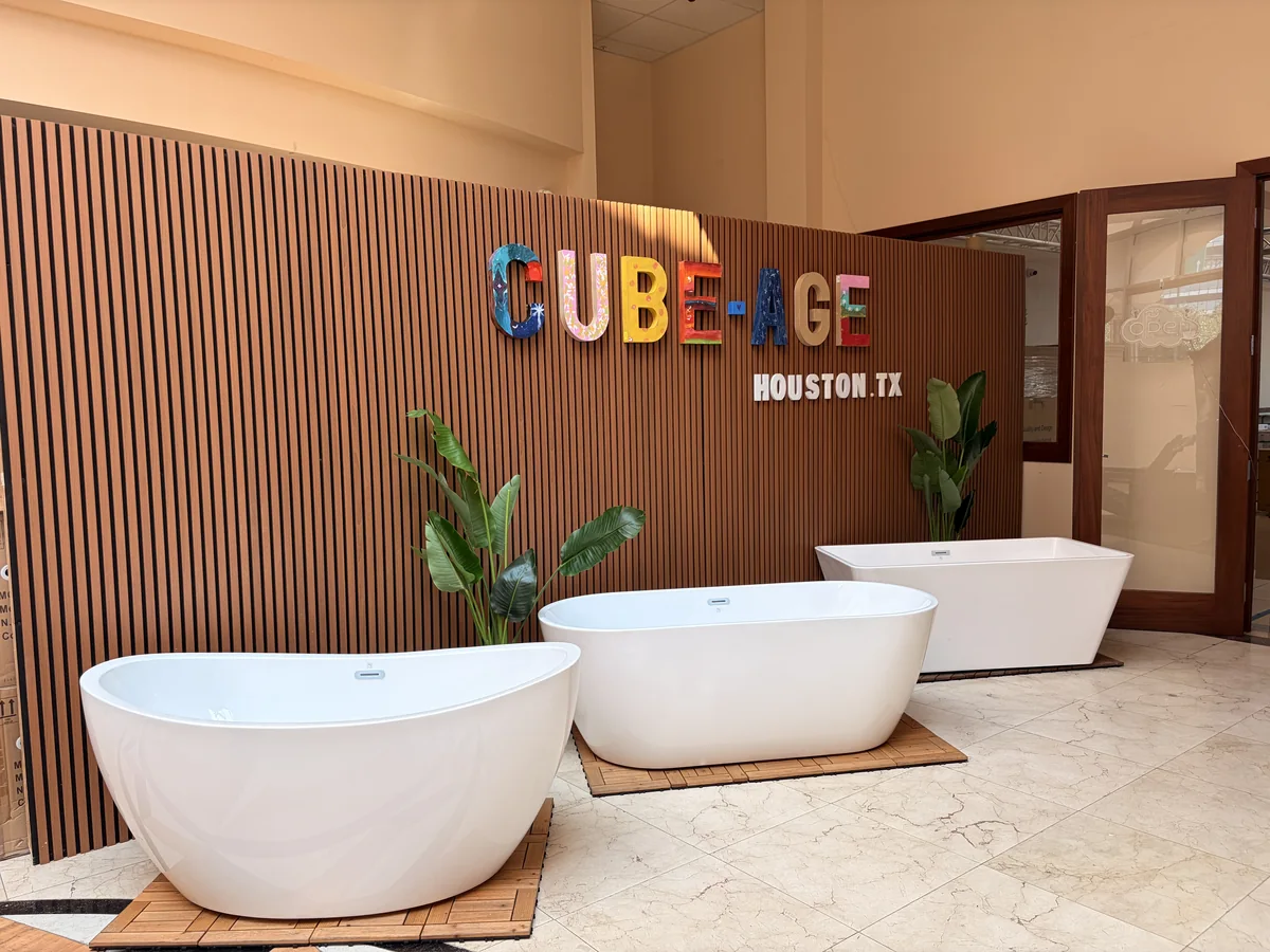 The CUBE-AGE brand wall inside the Houston showroom, with freestanding bathtubs in front of it